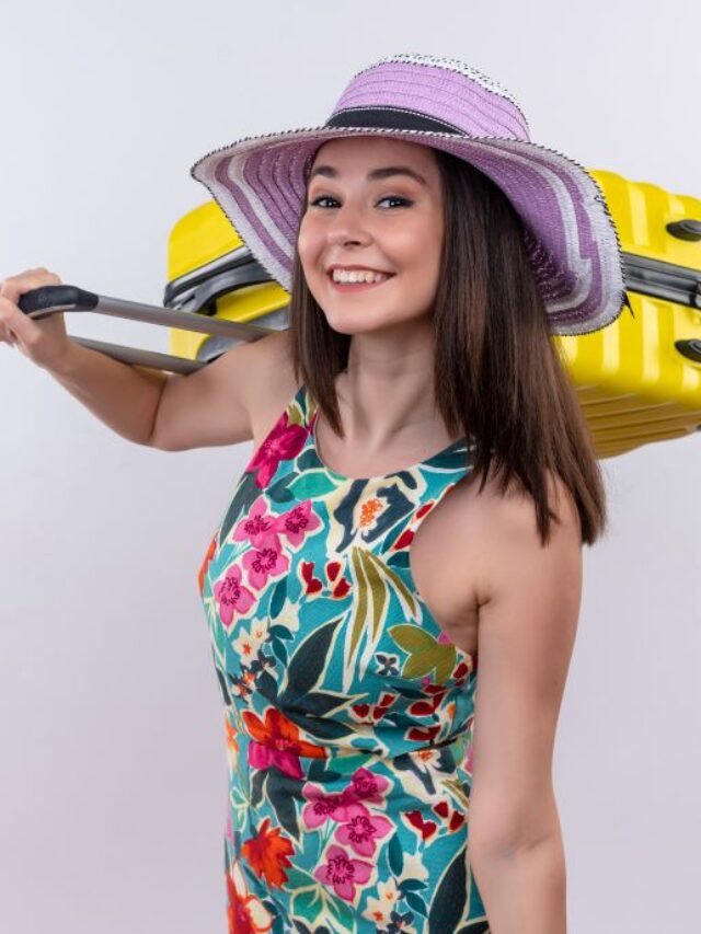 smiling-young-traveler-woman-holding-suitcase-isolated-white-wall