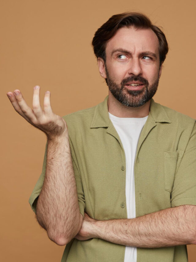 studio-portrait-bearded-man-posing-beige-background-raised-his-hand-with-confused-facial-expression