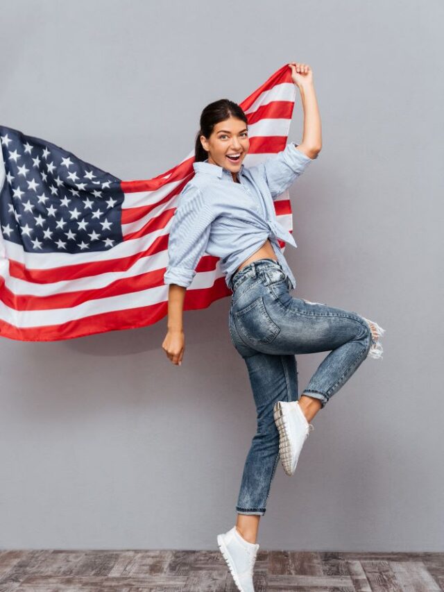 cheerful-young-happy-girl-holding-usa-flag-jumping-gray-wall