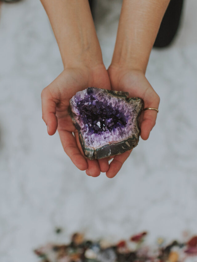 closeup-shot-girl-holding-multicolored-rock-her-hands-white-surface