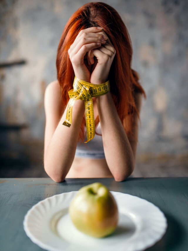 womans-hands-are-tied-with-measuring-tape-against-plate-with-apple-fat-calories-burning-concept-weight-loss